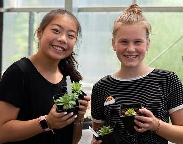 Two students hold plants at Skills Center course