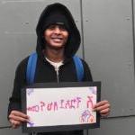 A student smiles for a photo with a sign that says welcome in Amharic