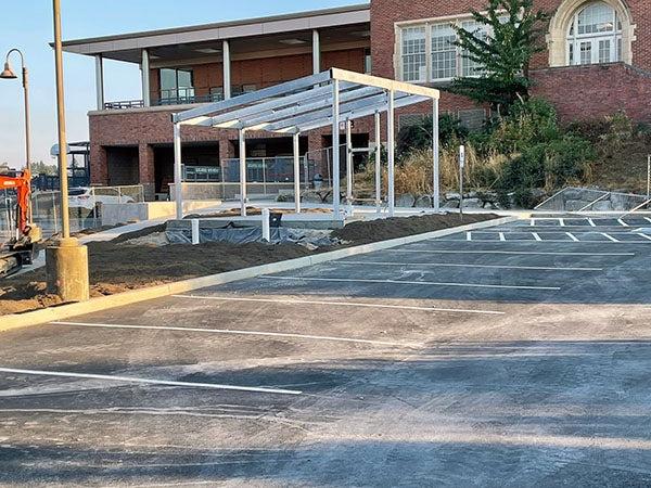 an asphalt parking lot with framing next to it for a shelter