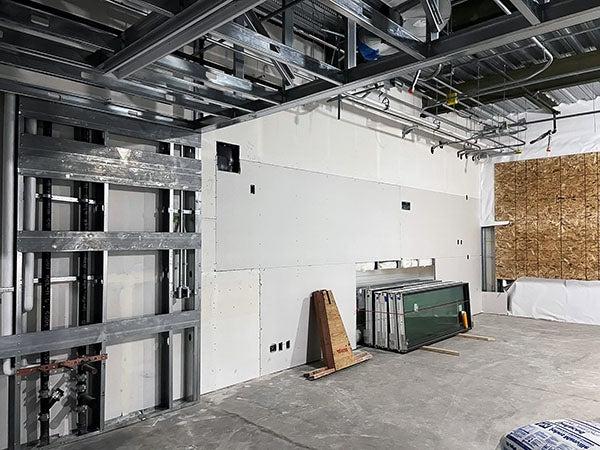 a partially completed room with wallboard that is not taped and a chipboard panel on one wall