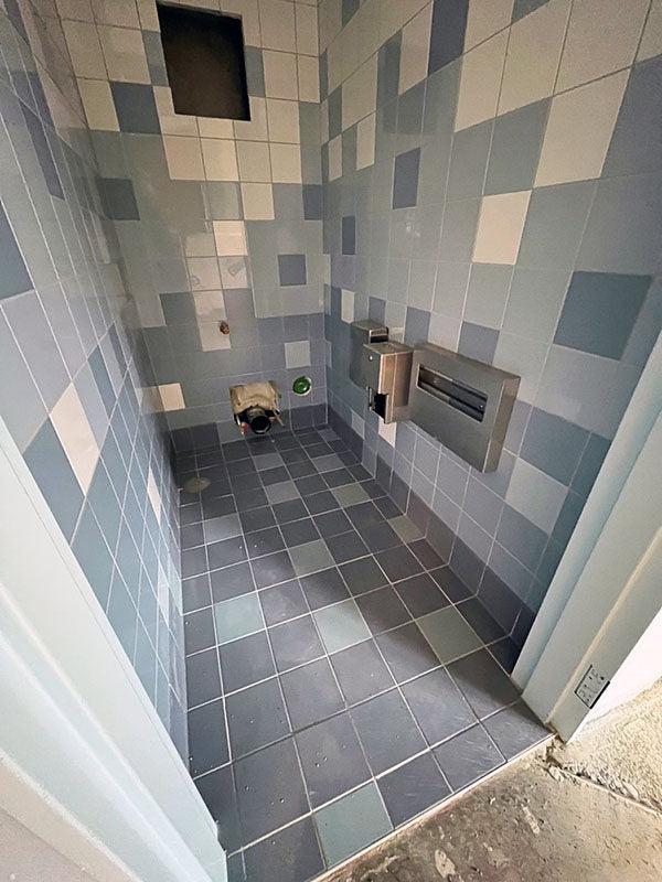 a small room has tile floors and walls