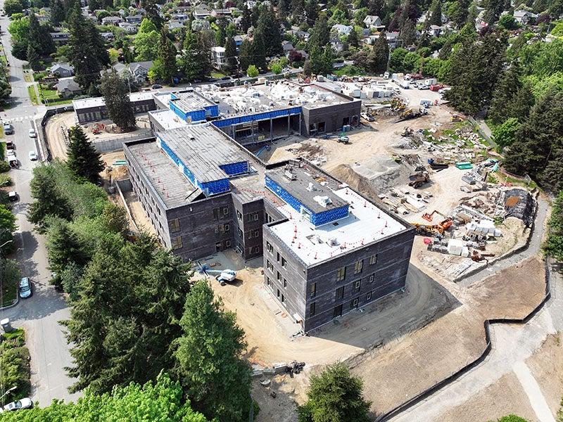 aerial of a large L shaped building with dirt and construction equipment around it