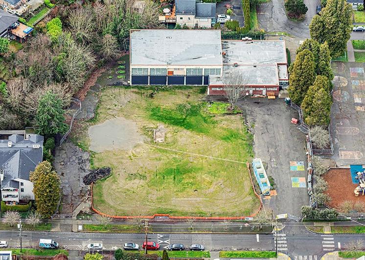 Aerial view of a large lot with ponding and grass next to a building