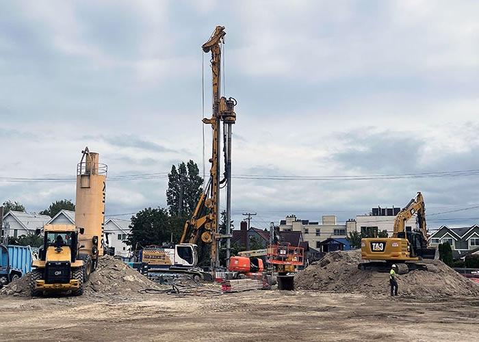 a grader, drill rig, and other construction equipment in a dirt construction site