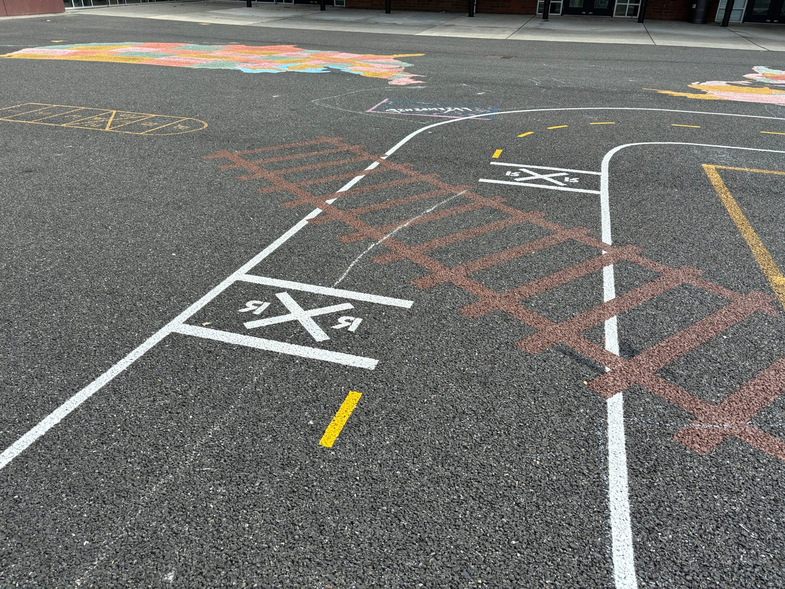 在柏油路面上绘制的微型道路 with painted railroad tracks.